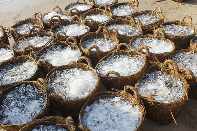 High angle view of dead fish and ice in baskets at beach