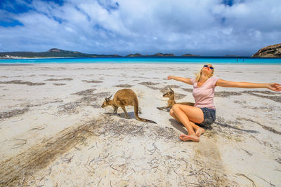 Woman with arms outstretched sitting at beach