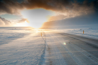 Scenic view of snow covered land against sky at sunset