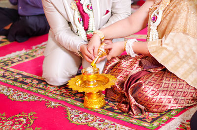 Midsection of couple pouring water during wedding ceremony