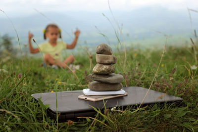 Cute girl relaxes in the mountains. stack of zen stones and digital gadget, laptop and mobile phones