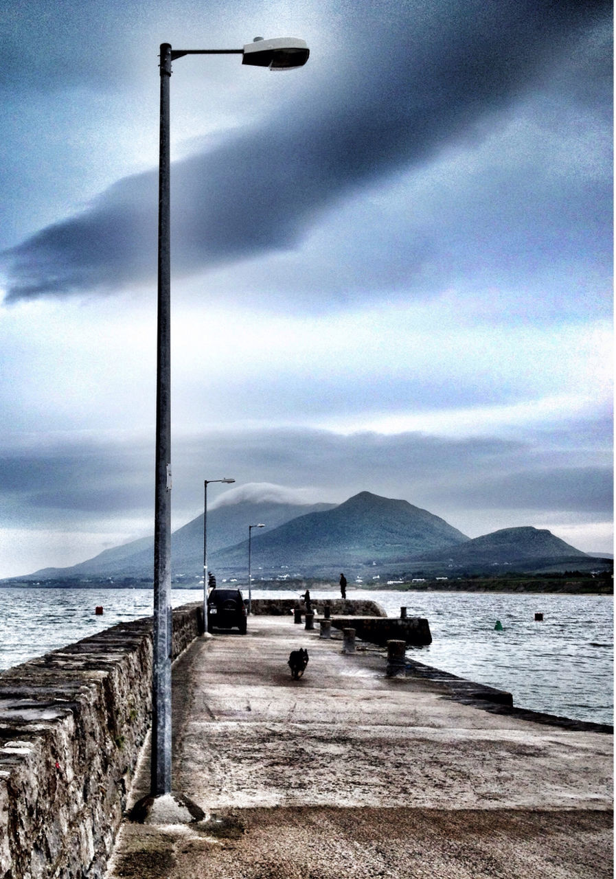 sky, mountain, sea, water, cloud - sky, cloudy, scenics, transportation, cloud, mountain range, tranquil scene, tranquility, beach, beauty in nature, nature, mode of transport, shore, street light, railing, pier