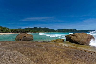 Rocks on beach against blue sky