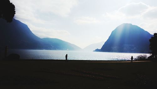 Silhouette people by sea against sky