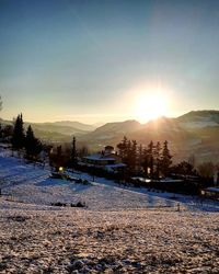 Snow covered landscape against sky during sunset