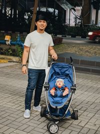 Portrait of young man with baby in stroller