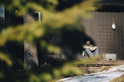 Mature man sitting on porch during sunny day in winter