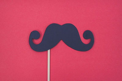 Close-up of mustache prop on red background