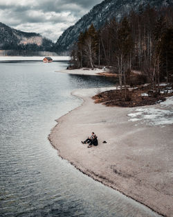 High angle view of couple sitting by lake against trees