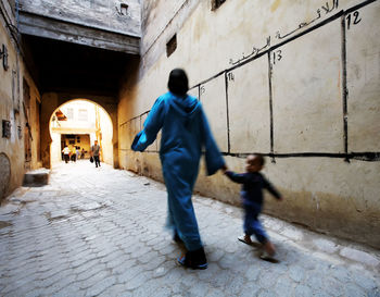 Blurred motion of mother with son walking by election wall