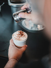 Barista preparing a delicious cinnamon espresso coffee on small white cup. cinnamon on top of cream