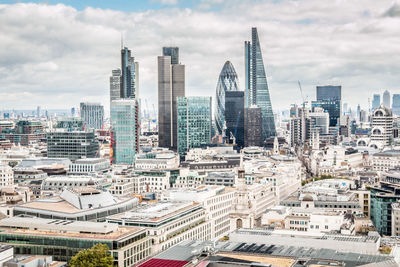 Aerial view of buildings in city against cloudy sky