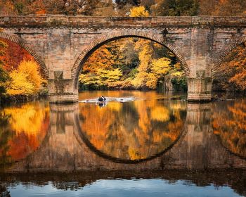 Arch bridge over river during sunset