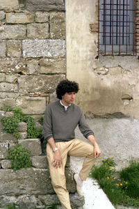 Young man looking down while standing against wall