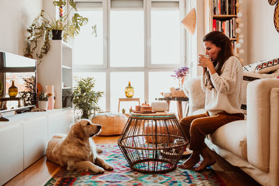 Young woman with dog sitting on table at home