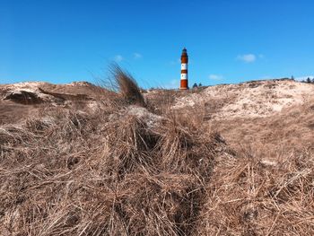 Lighthouse on field against sky