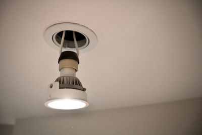 Low angle view of illuminated lamp on wall at home