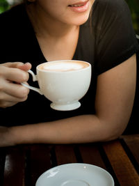 Midsection of woman holding coffee cup on table
