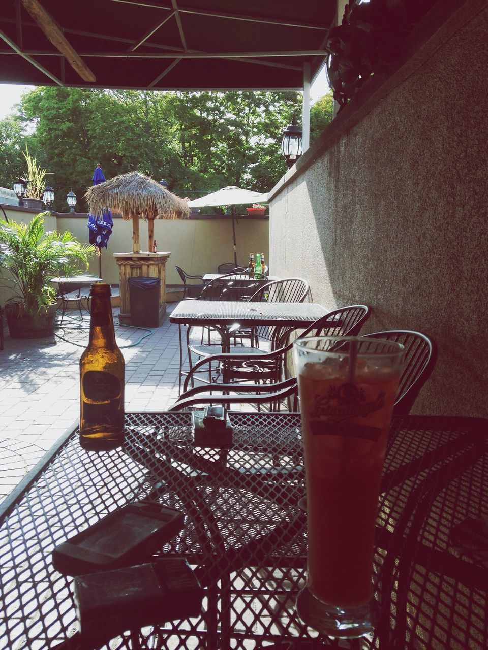 table, drink, chair, food and drink, drinking glass, restaurant, freshness, potted plant, refreshment, indoors, absence, place setting, sunlight, empty, still life, sidewalk cafe, plant, glass - material, day, vase