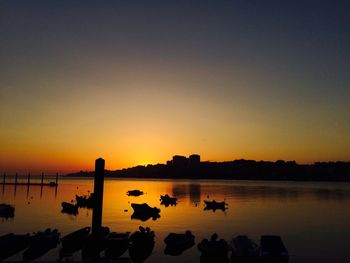 Silhouette people on sea against clear sky during sunset