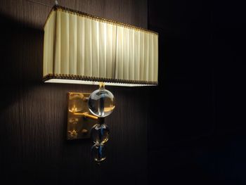 Close-up of illuminated electric lamp on table in darkroom at home