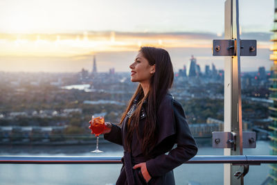 Young woman standing by railing in city