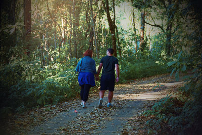 Rear view of women walking on footpath in forest