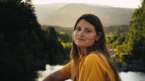 Portrait of young woman against trees