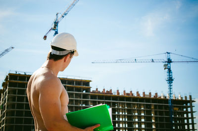 Shirtless man standing against construction buildings