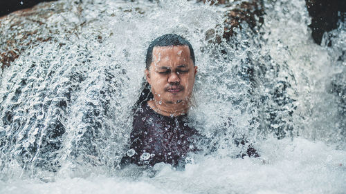 Man sitting amidst flowing water