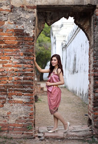 Portrait of woman standing against brick wall