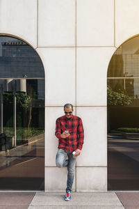 Portrait of young man standing against building