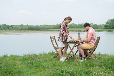 Side view of woman sitting on grassy field
