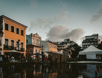 Buildings by river against sky