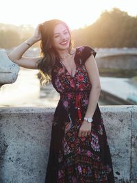 Smiling beautiful woman leaning on concrete against retaining wall