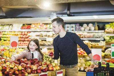 Father and daughter buying fresh apples in supermarket