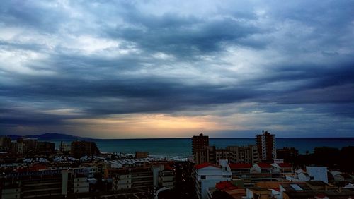 Buildings by sea against sky at sunset