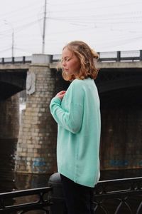 Young woman standing against wall in city