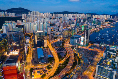 Aerial view of illuminated street amidst buildings in city at dusk