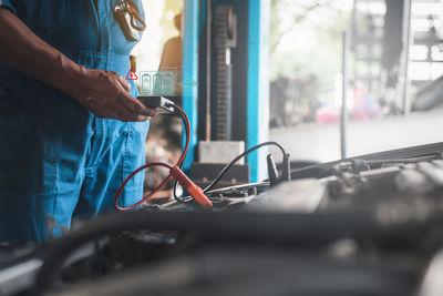 Midsection of mechanic repairing car