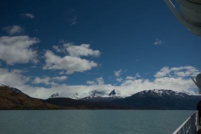 Scenic view of sea by snowcapped mountains against sky