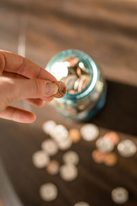 Woman putting coins into jar, saving money, penny pinching