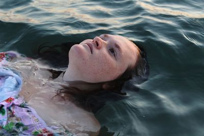 High angle portrait of woman lying in swimming pool