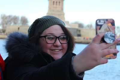 Smiling young woman taking selfie with smart phone
