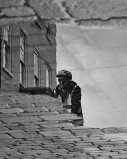 Man walking on footpath by street against building