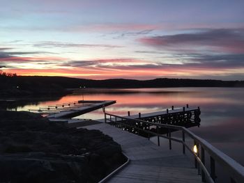 Pier over lake against sky at sunset