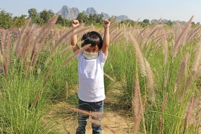 Asian boy stand in the meadow with his hand raised.