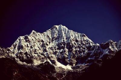 Low angle view of snow covered mountain against blue sky