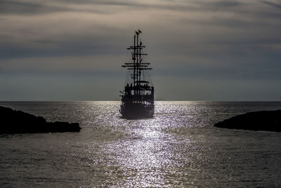 Silhouette sailboat sailing in sea against sky