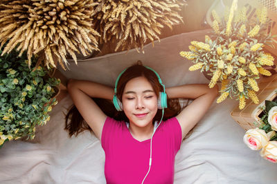 High angle view of woman listening music through headphones while lying on floor